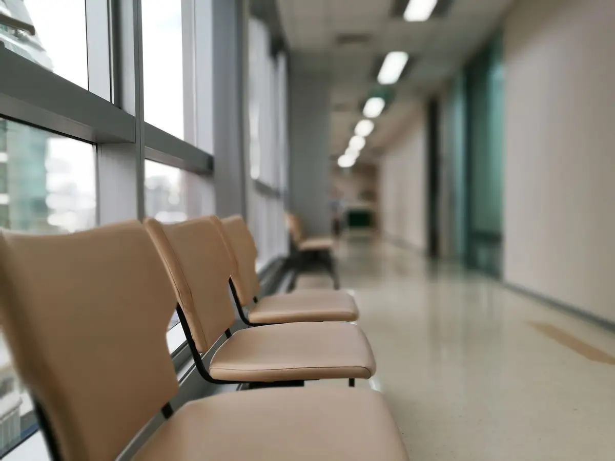 A row of empty chairs along a quiet hospital corridor.